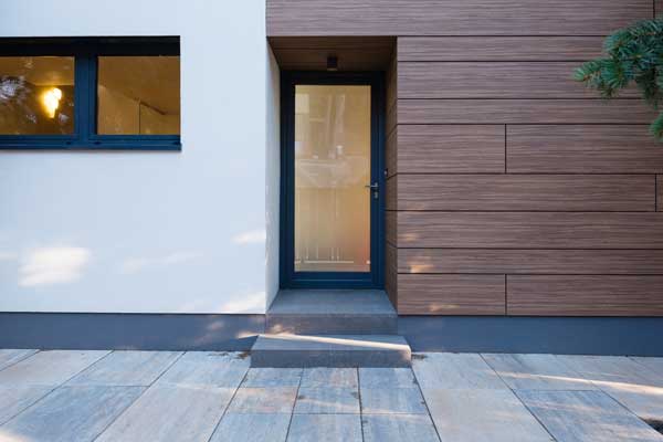 Façade d'une maison moderne en béton et en bois. Porte d'entrée en verre.